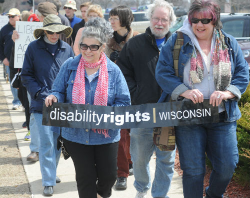 group of people for disability rights marching with sign that says DRW