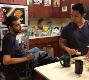 Man in wheelchair with his personal attendant making lunch in the kitchen.